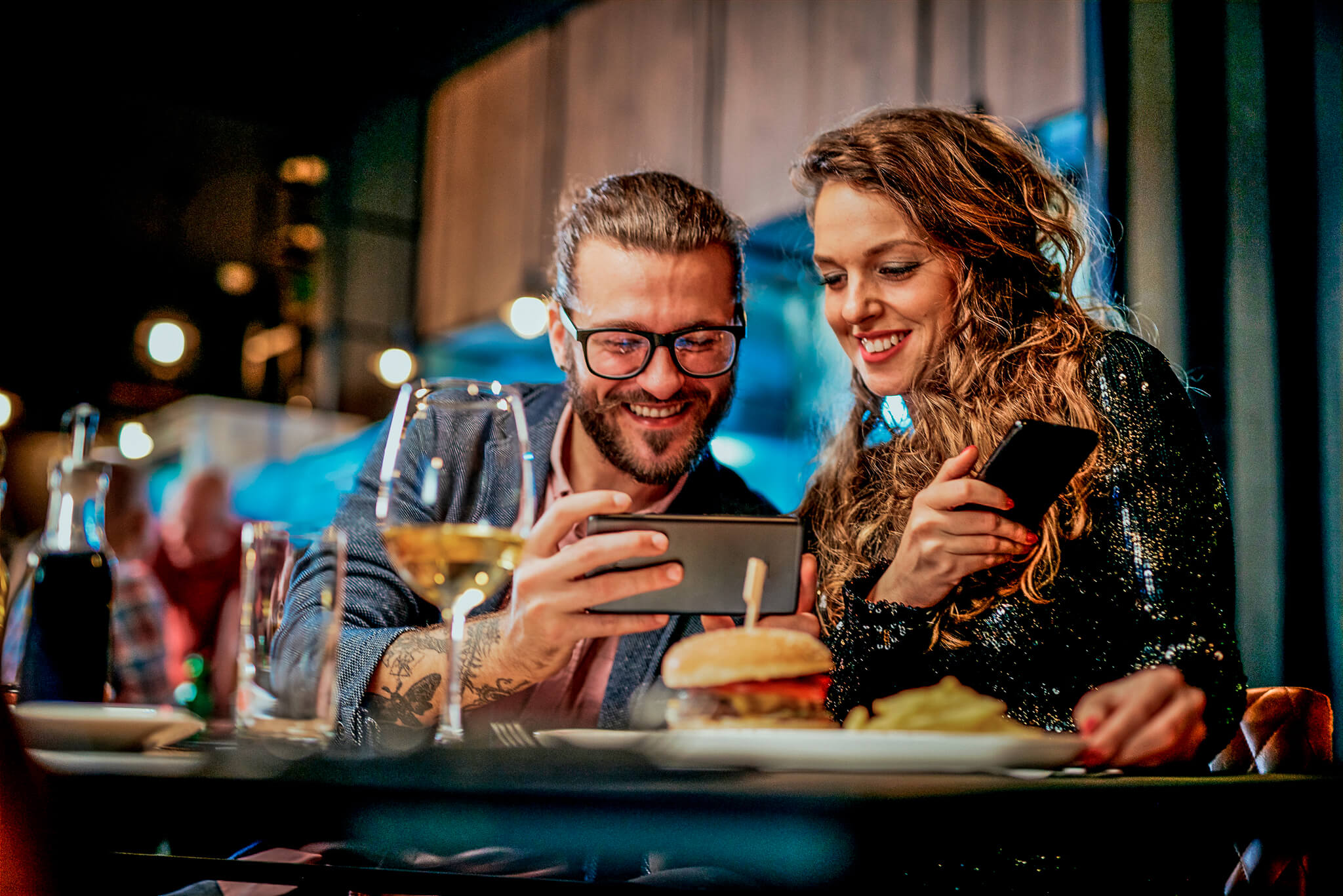 A young couple sitting infront of their smart phone and checking the restaurant's Instagram presence.