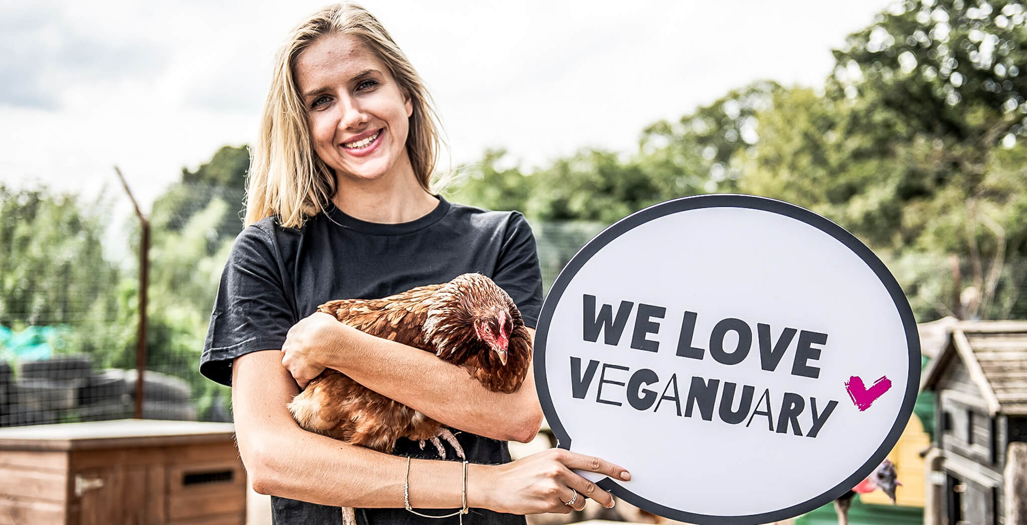 Woman holding chicken and sign "We love Veganuary"